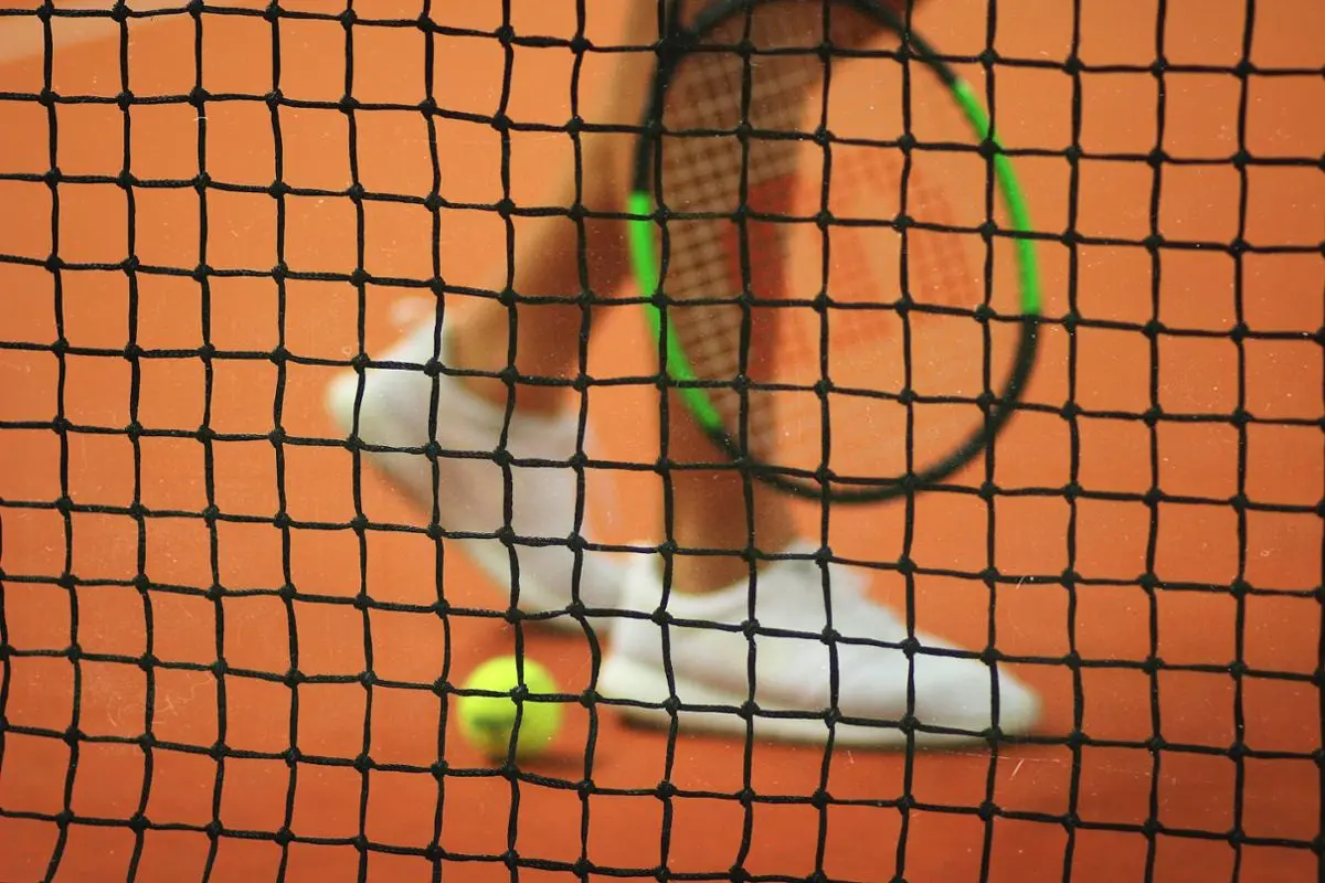 Un jugador de tenis camina por el centro de la cancha cerca de la red.